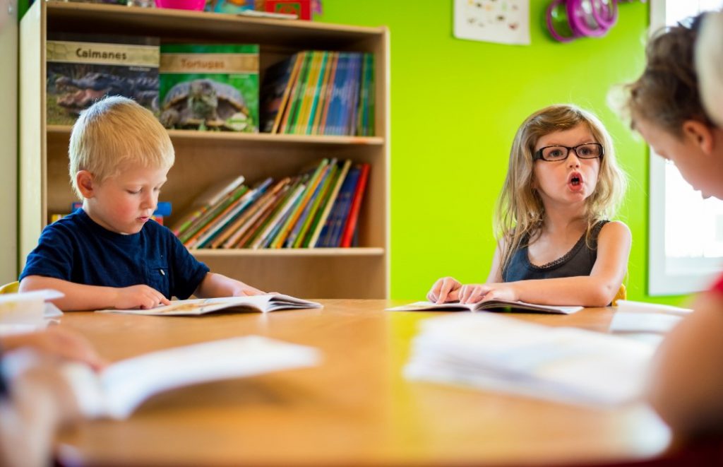 Two children looking at books to be introduced to letters of the alphabet as a part of a kindergarten readiness strategy