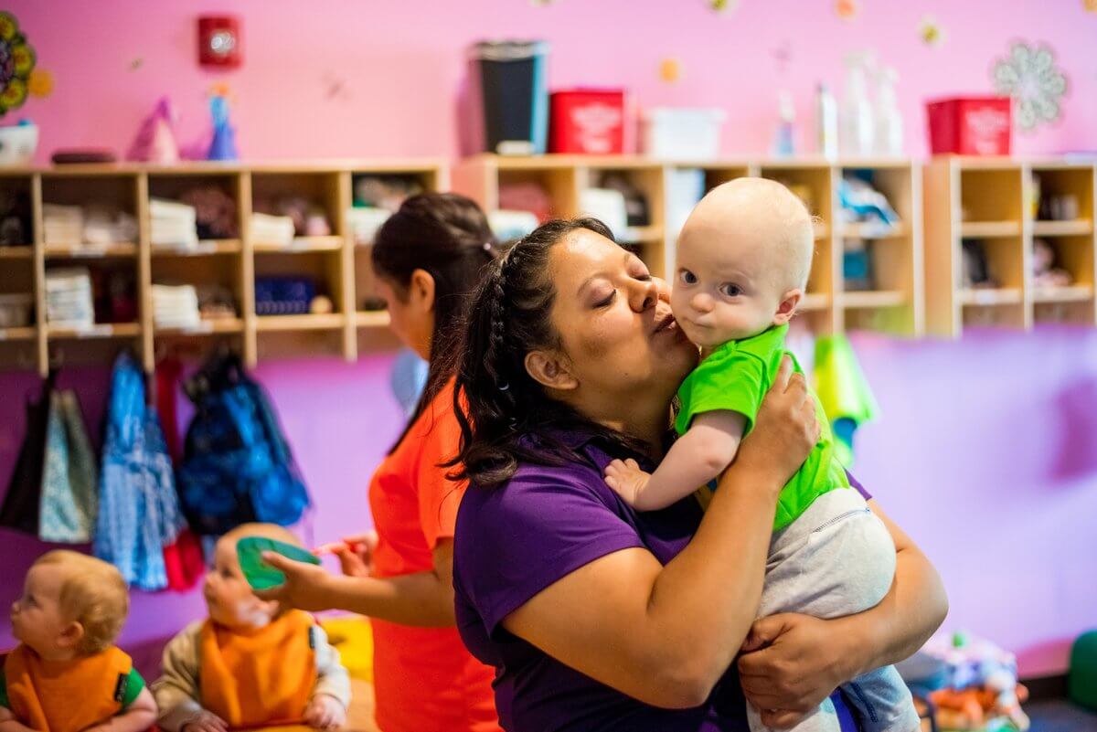 Daycare teacher at Casa De Corazon comforting a baby to help ease separation anxiety while transitioning to daycare