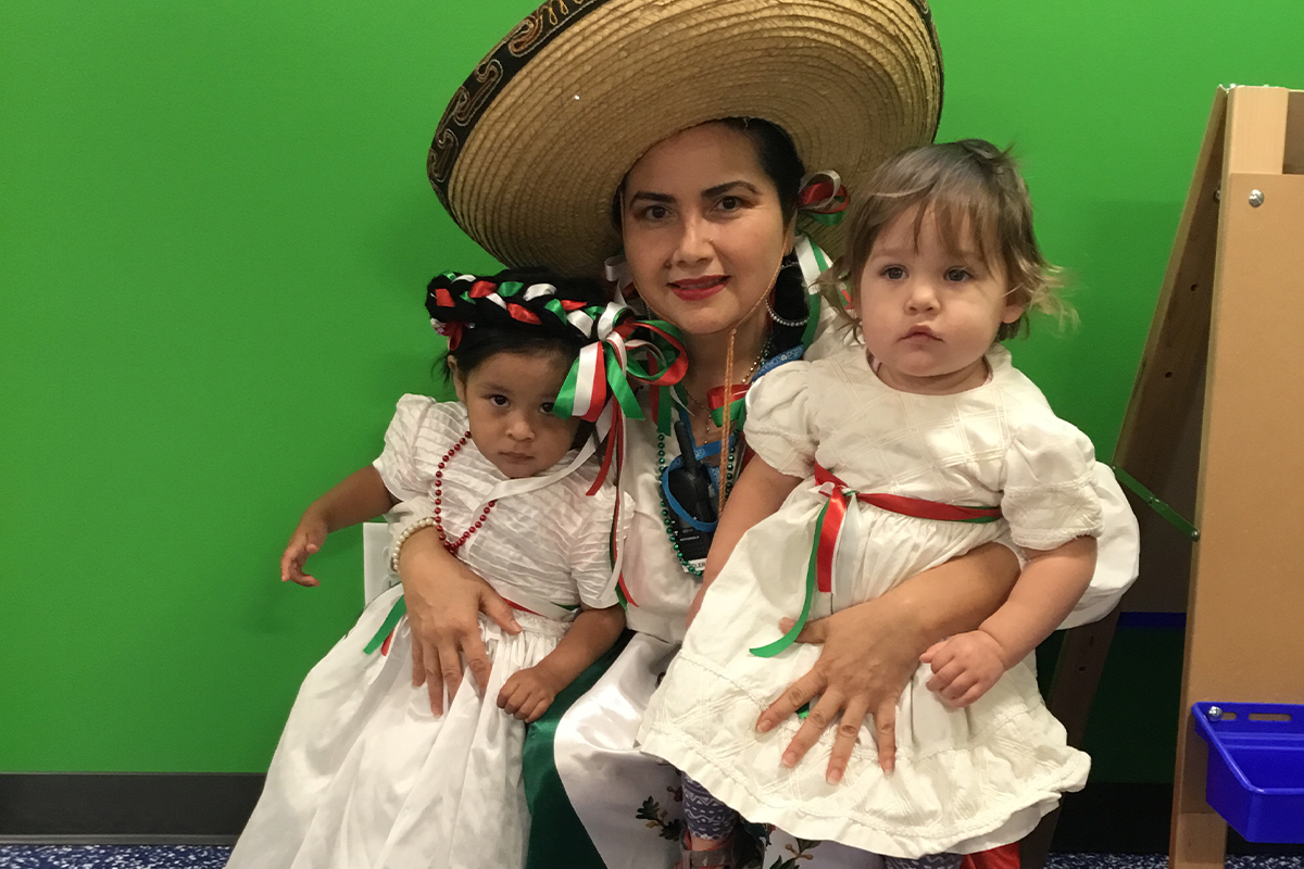 teacher holding two children at Casa and sharing her culture for the interculturality
