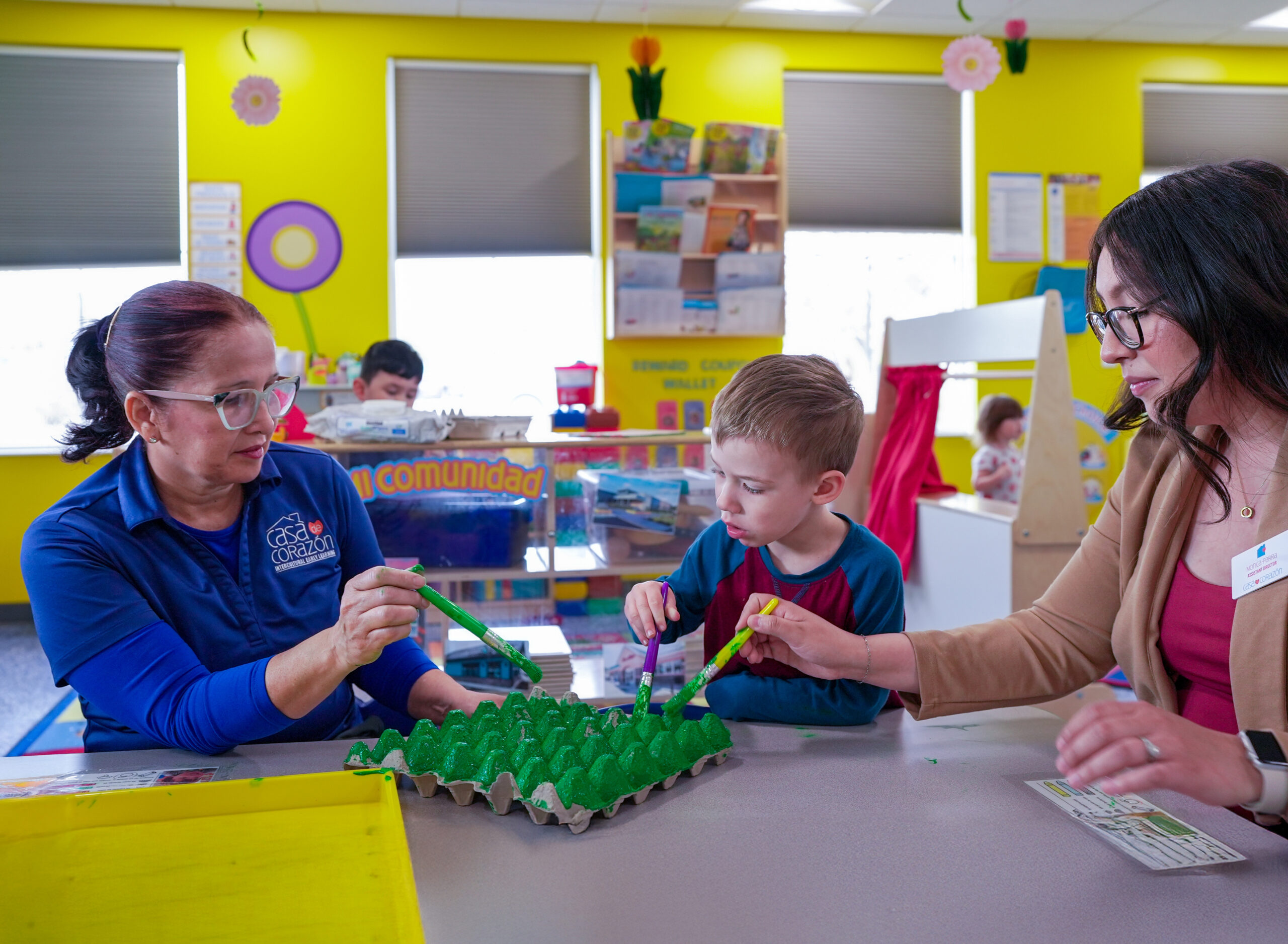 Two teaching professionals with a child at daycare